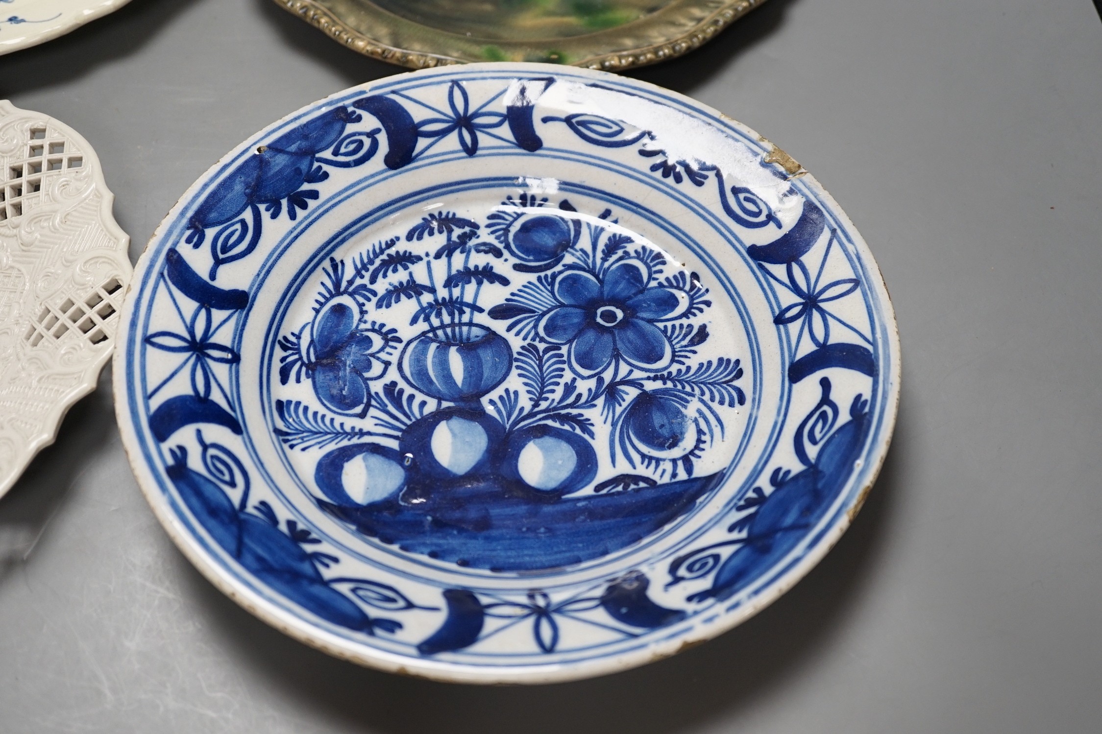 A Staffordshire salt glaze plate with pierced border, a Staffordhire tortoiseshell painted plate, a creamware underglaze blue plate and a Dutch delft plate, salt glazed plate 21 cms diameter